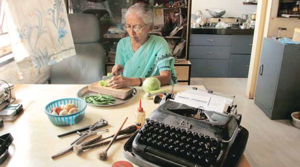 Schreibmaschine auf Tisch, auf dem ältere Frau Gemüse schneidet